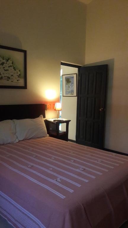 een slaapkamer met een groot bed en een paarse deken bij villa Clara in Los Róbalos