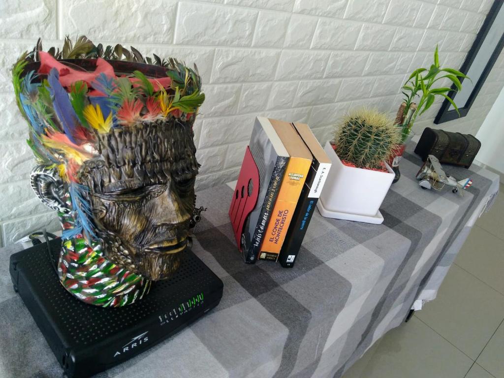 a statue of a head on a table with books and plants at A minutos del centro Con cochera in Trujillo