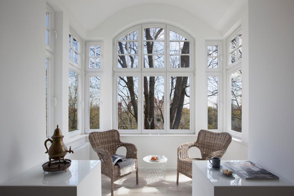 a room with three windows and a table and chairs at RJ Apartments Chopina in Sopot