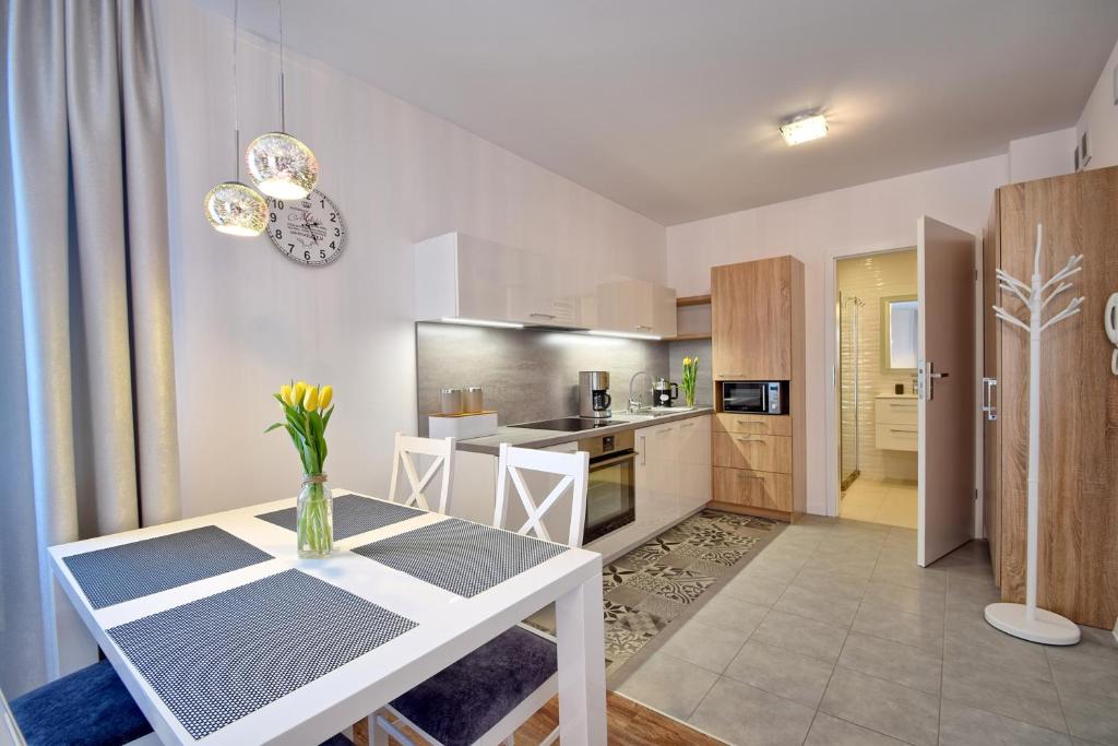 a kitchen and living room with a white table and chairs at Bliżej Morza 16 PREMIUM in Kołobrzeg