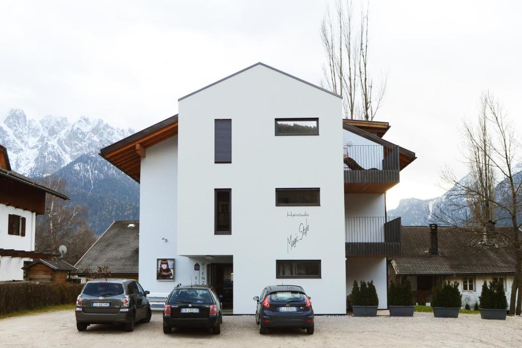 un bâtiment blanc avec des voitures garées devant lui dans l'établissement Villa Rienzner, à Dobbiaco
