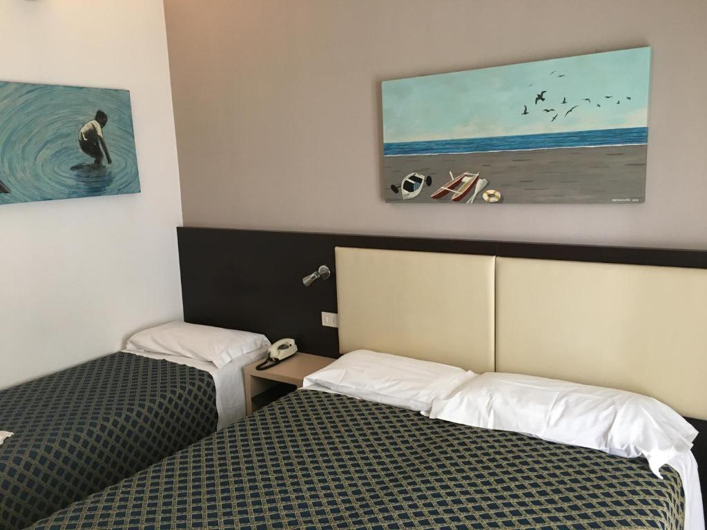 een kamer met 2 bedden en een schilderij aan de muur bij Hotel Rudy Cervia in Cervia