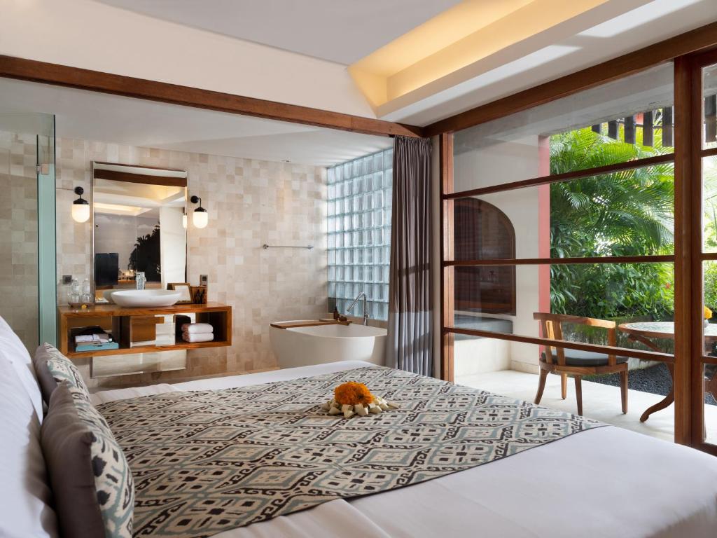 a bedroom with a bed and a bathroom with a tub at Amnaya Resort Kuta in Kuta