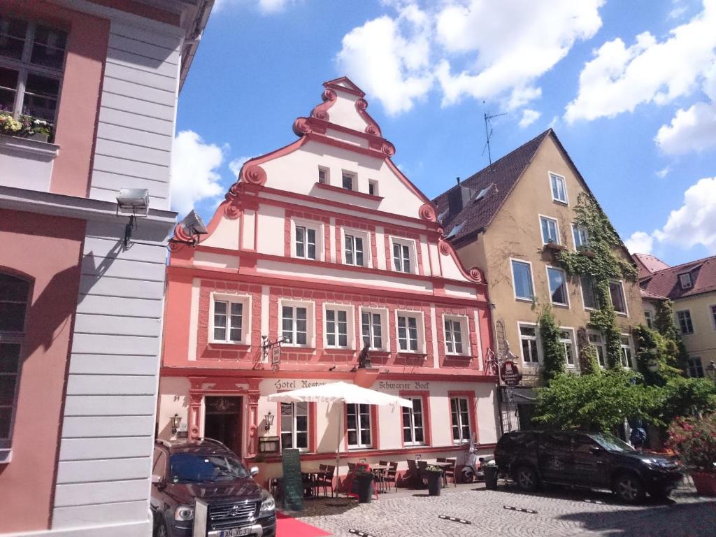 un bâtiment rouge avec une tourelle dans une rue dans l'établissement Boutique Hotel & Bio Wirtshaus Schwarzer Bock, à Ansbach