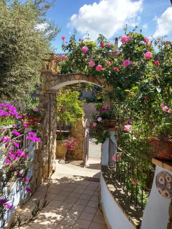 un arco con fiori rosa su un muro di pietra di Graziosissima villa a Capitana