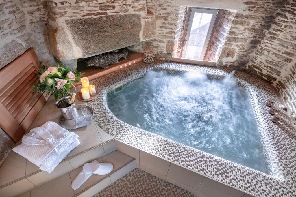 uma banheira de hidromassagem numa casa de banho com janela em La Vinotière Chambres Appartements Spa em Le Conquet