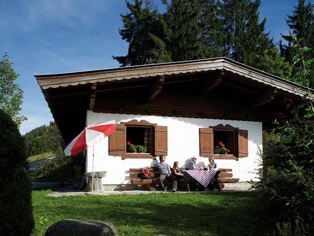 a group of people sitting on a bench in front of a house at Ferienhaus Soregina in Ellmau