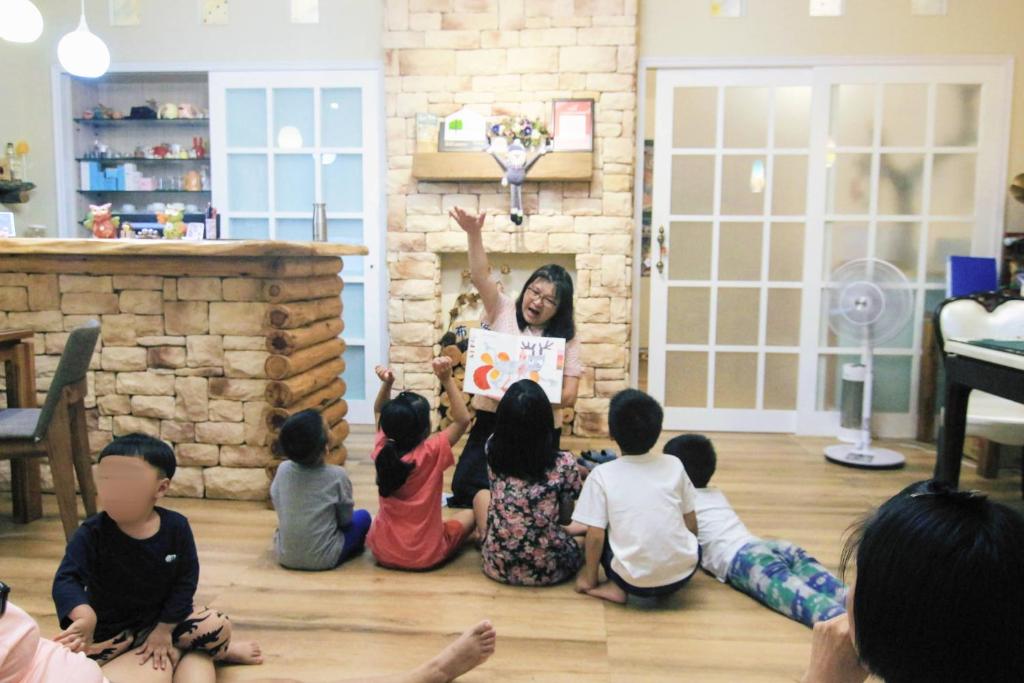 uma mulher lendo um livro para um grupo de crianças em Books & Woods Bed and Breakfast em Taitung City