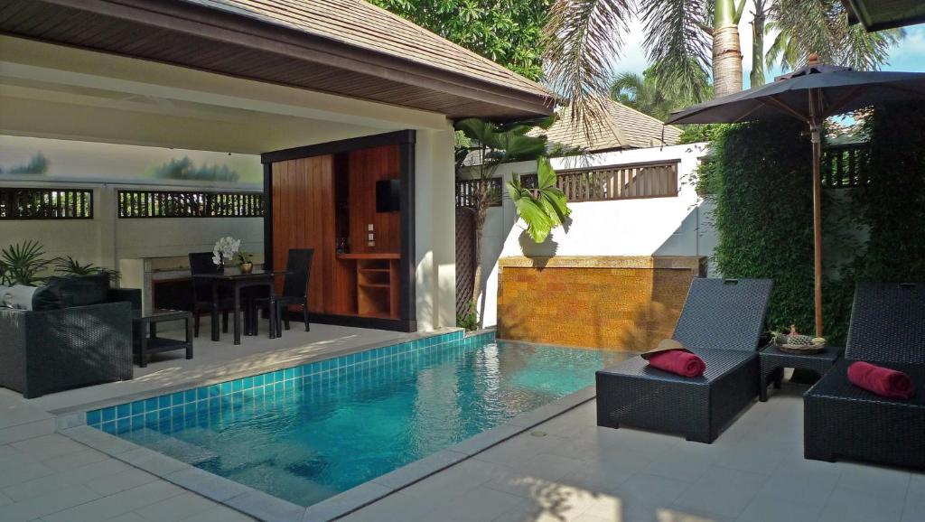 a swimming pool with chairs and an umbrella next to a house at Samui Boat Lagoon in Choeng Mon Beach