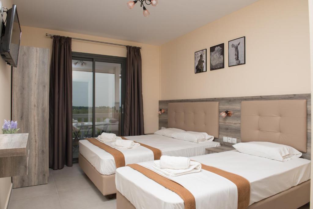 a hotel room with two beds and a balcony at INO Luxury Rooms in Paralia Katerinis
