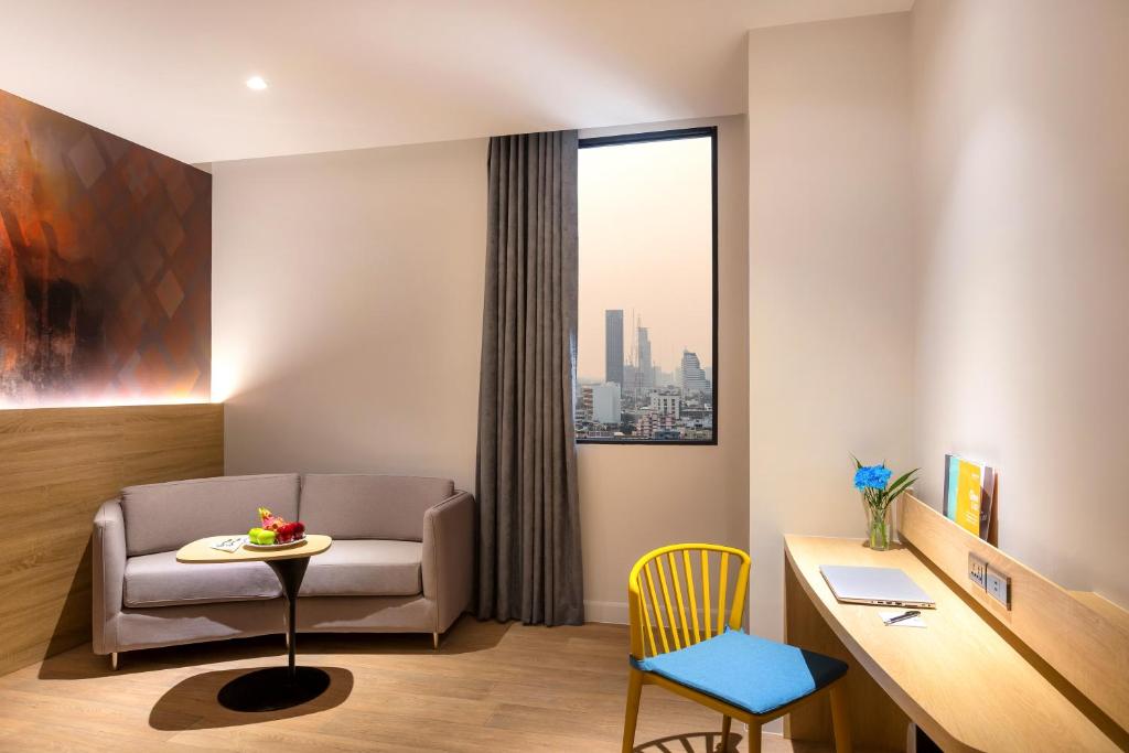 A compact in-room work area beside a sofa and a tall city-view window.