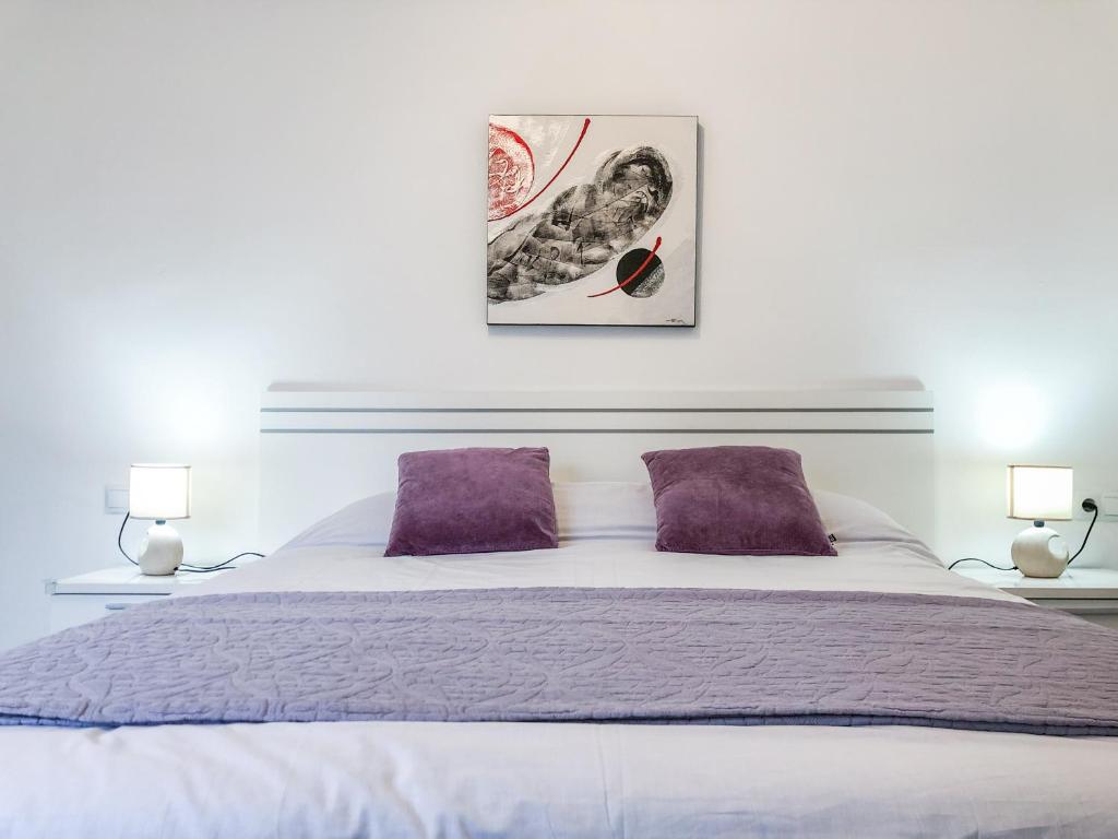 - une chambre avec un grand lit et des oreillers violets dans l'établissement Luminoso piso + balcón en Valencia, à Valence