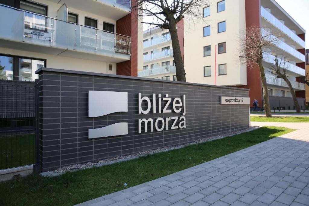 a sign in front of a building at Apartamenty BLIŻEJ MORZA Siłownia i Taras Widokowy Kołobrzeg by Renters in Kołobrzeg