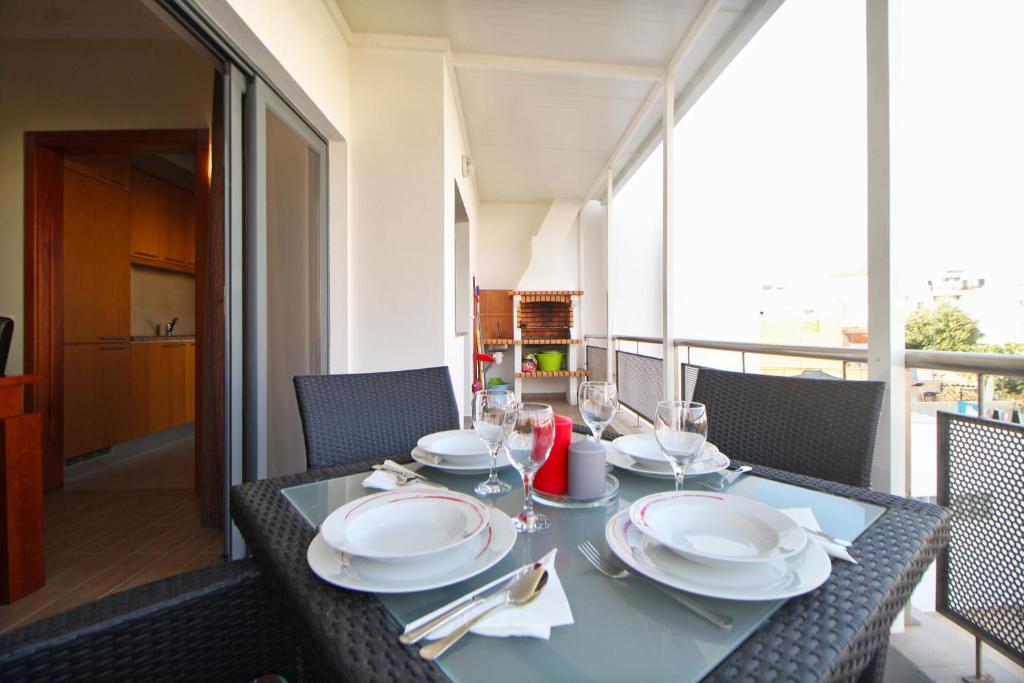 a table with plates and glasses on a balcony at Prestige for Home Apt Vista Mar 2 Quarteira in Quarteira