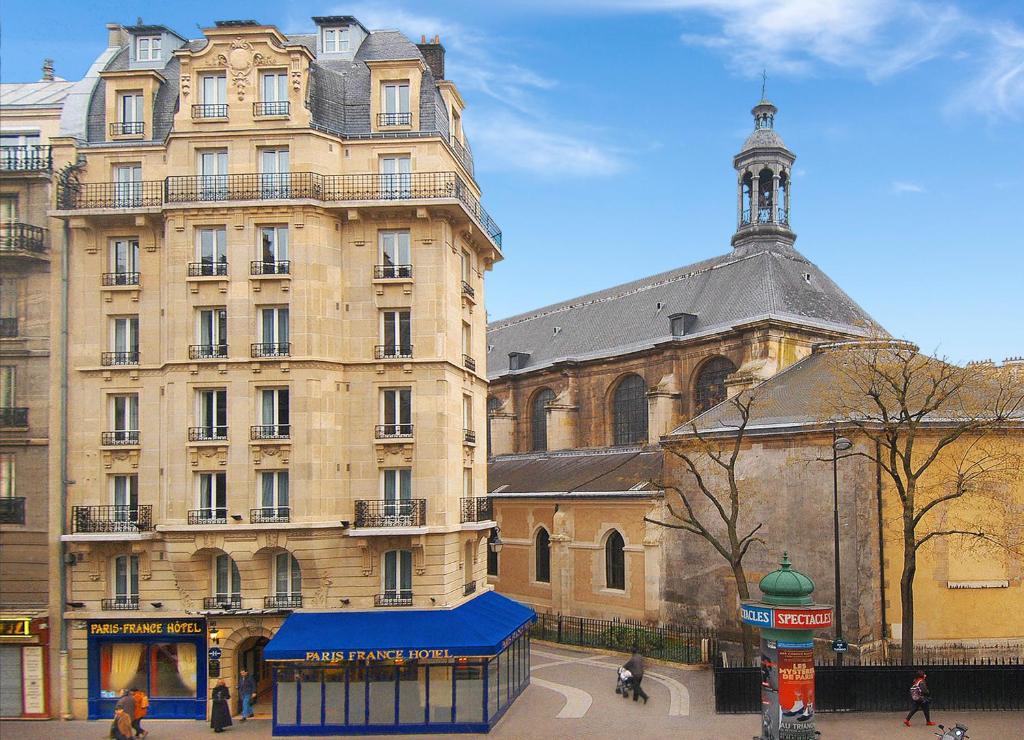un gran edificio con una tienda azul delante de él en Paris France Hotel, en París