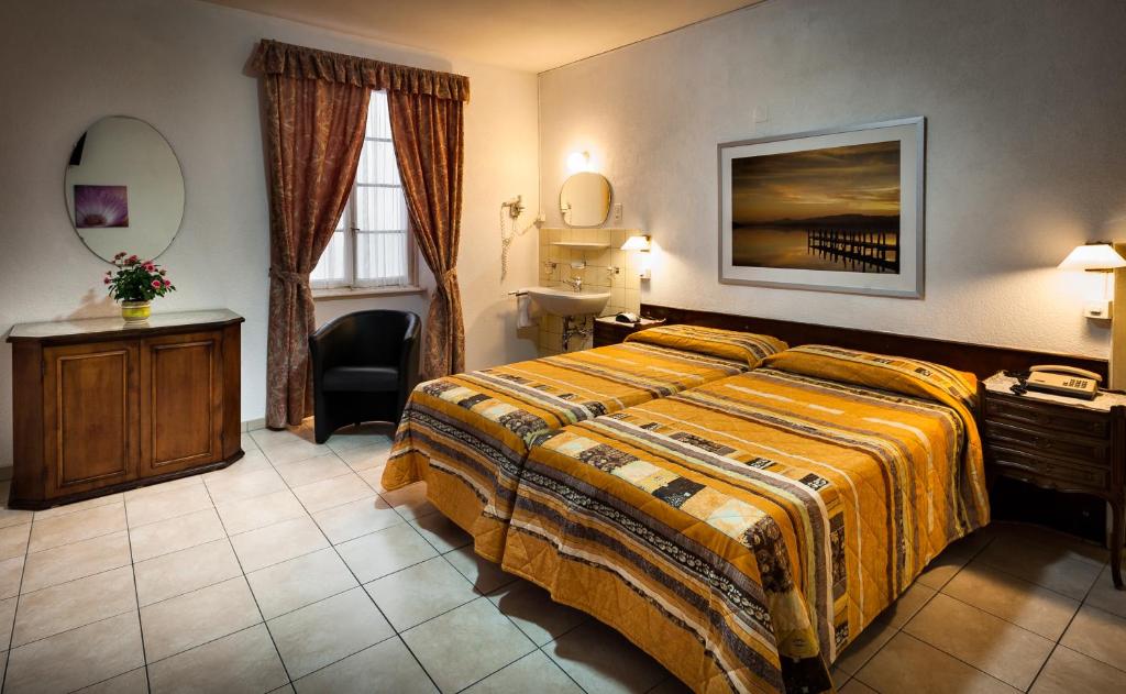 a hotel room with a bed and a desk and a mirror at EasyRooms dell'Angelo in Locarno