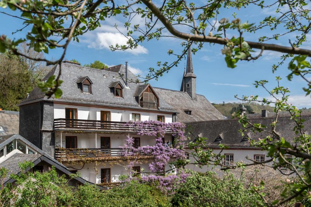 un bâtiment avec des fleurs violettes devant lui dans l'établissement Hotel Heintz, à Vianden