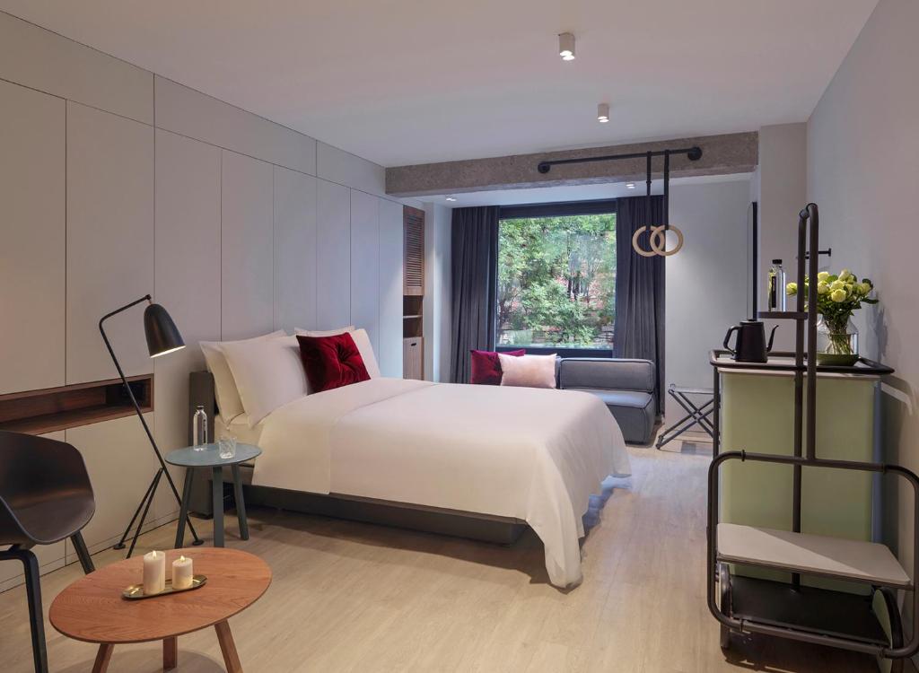 a bedroom with a large white bed and a window at Stey Wangfujing Hotel in Beijing