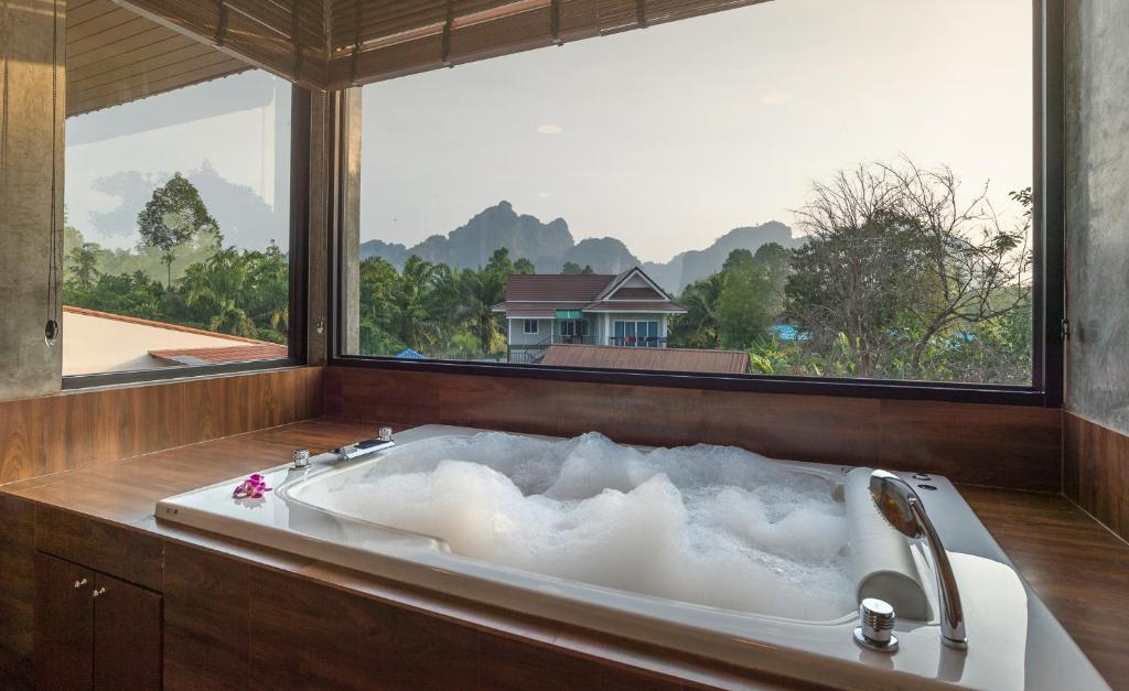 a bath tub with a large window in a bathroom at The Country Villa in Ao Nang Beach