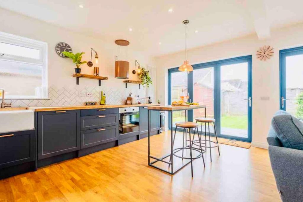 a kitchen with blue cabinets and a table and stools at Firtree Cottage New Forest in Hordle