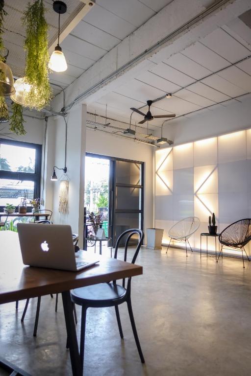A shared lounge workspace with a laptop table, chairs, and garden-facing glazing.