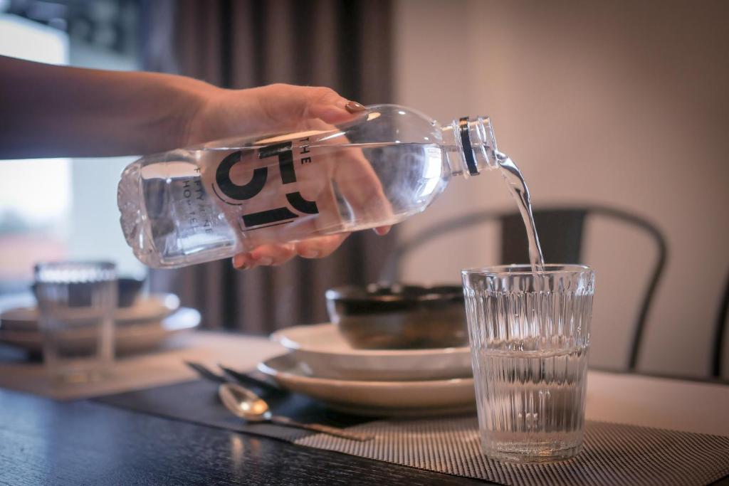 A styled dining table with bottled water, a glass, coffee and crockery.