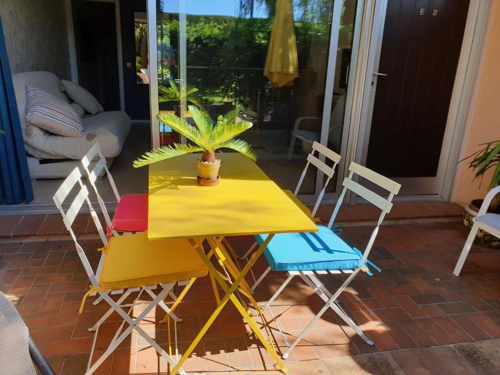 マンドリュー・ラ・ナプールにあるGrand 2 pièces plain pied avec jardin et terrasseの黄色のテーブルと椅子が並ぶパティオ