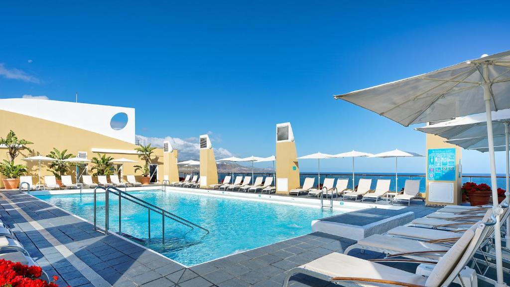 a swimming pool with chairs and umbrellas at a resort at Bull Reina Isabel & SPA in Las Palmas de Gran Canaria