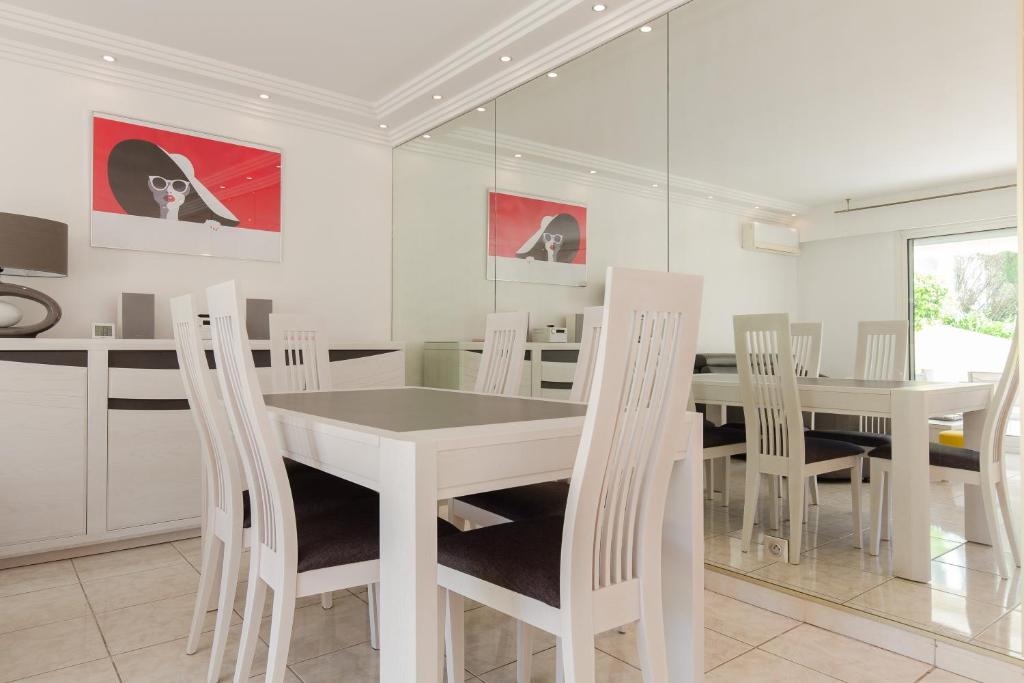 uma sala de jantar branca com uma mesa e cadeiras brancas em Villa AD’ALTA em Cannes