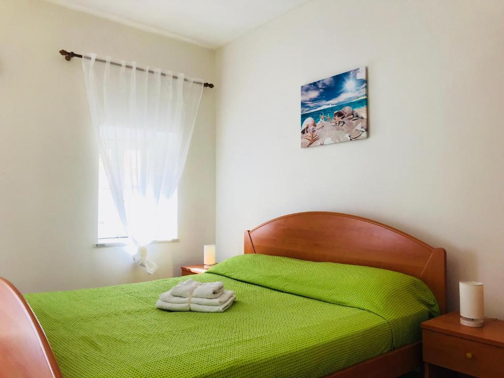 1 dormitorio con 1 cama verde y 2 toallas en DolceVacanza, en Cefalú