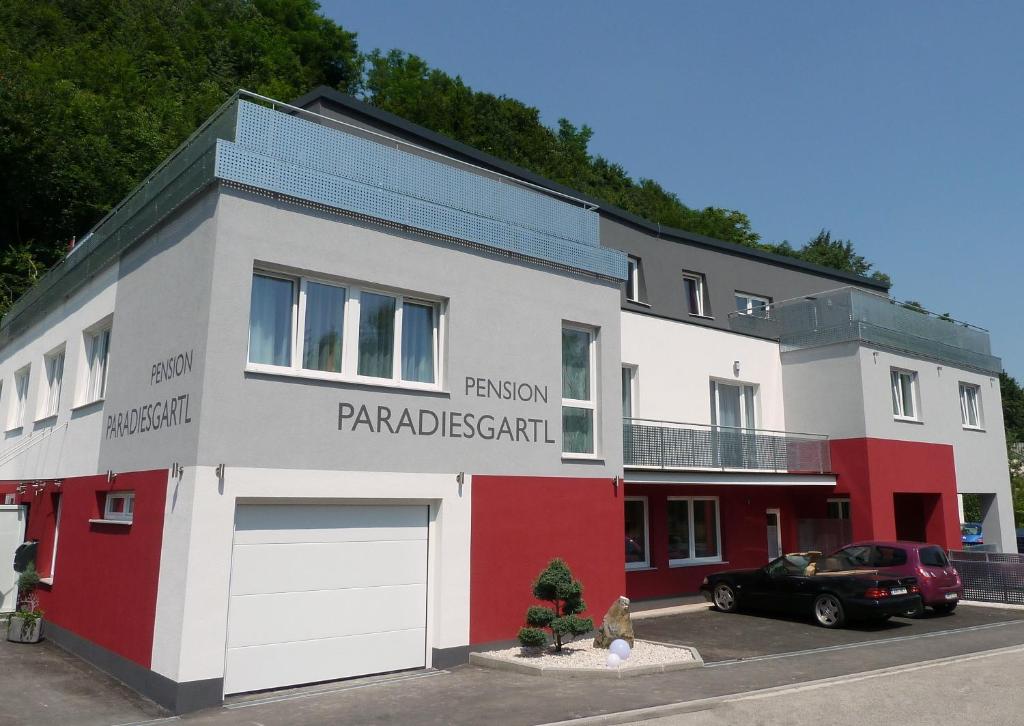 ein weißes und rotes Gebäude mit einem Auto, das vorne parkt in der Unterkunft Frühstückspension Paradiesgartl in Amstetten
