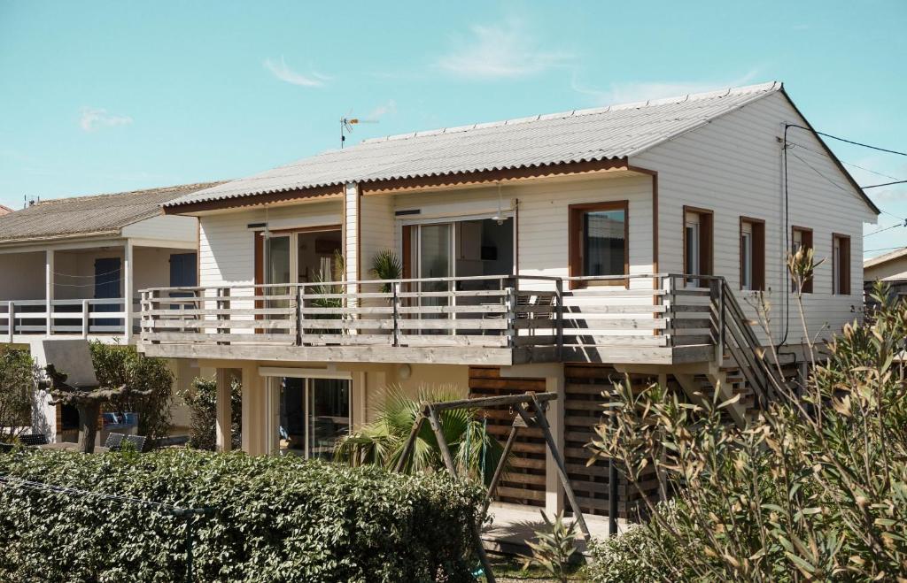 een wit huis met een veranda en een balkon bij Le Chalet du Papa in Gruissan