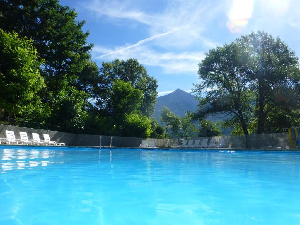 une piscine avec des chaises et une montagne en arrière-plan dans l'établissement Camping, Hôtel De Plein Air Les Cariamas, à Châteauroux-les-Alpes