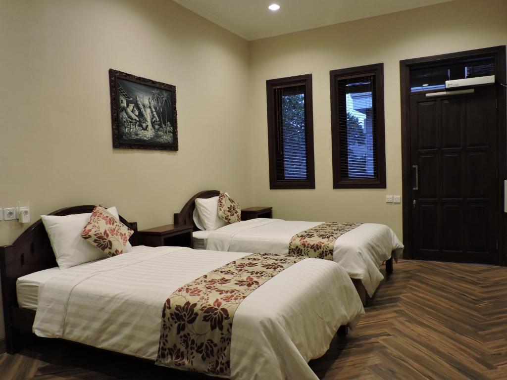 um quarto de hotel com duas camas e uma janela em Accessible Penyaringan em Sanur