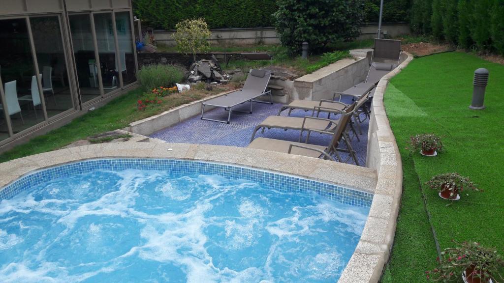 une grande piscine avec des chaises et une pelouse dans l'établissement Albergue Turistico Salceda, à A Salceda