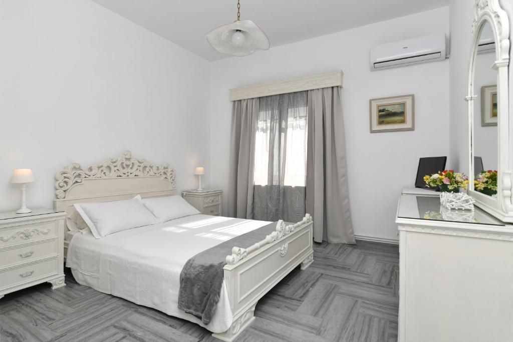 a white bedroom with a bed and a mirror at Cozy house in Naousa in Naousa