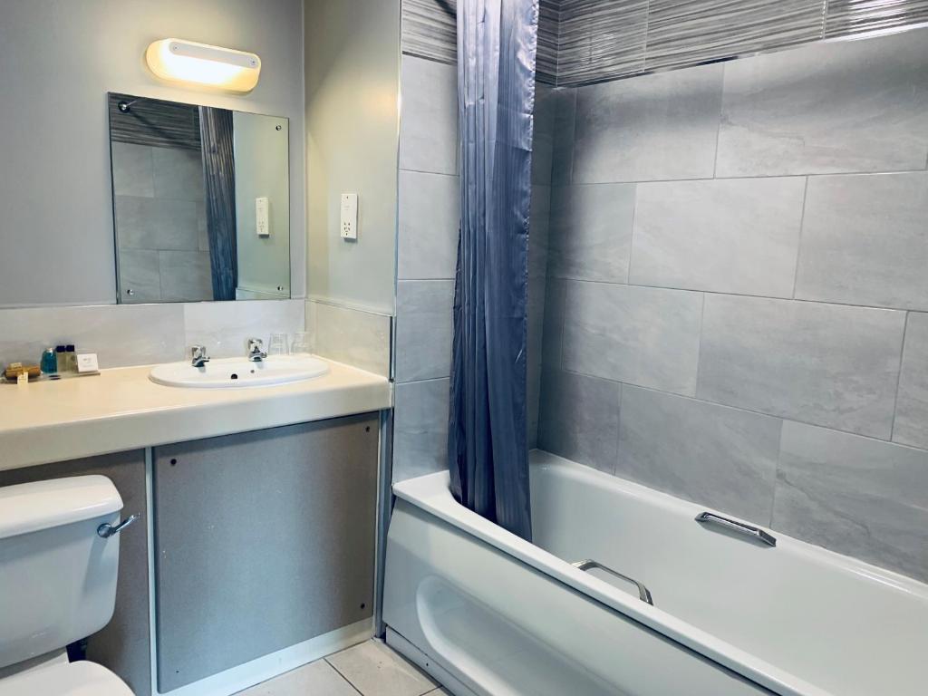 班布里奇的住宿－The Bannville Hotel，浴室配有盥洗盆、卫生间和浴缸。