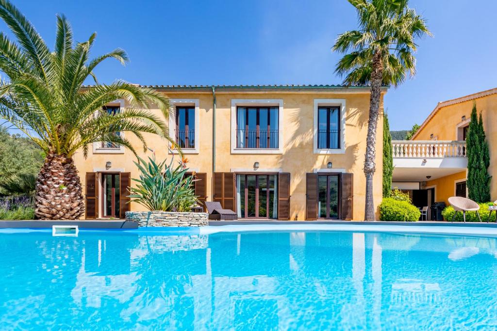 una gran piscina frente a una casa con palmeras en Finca Cabrita en Andratx