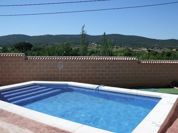 a large swimming pool next to a brick wall at Casa Rural Las Canteras de Cabañeros in Retuerta de Bullaque