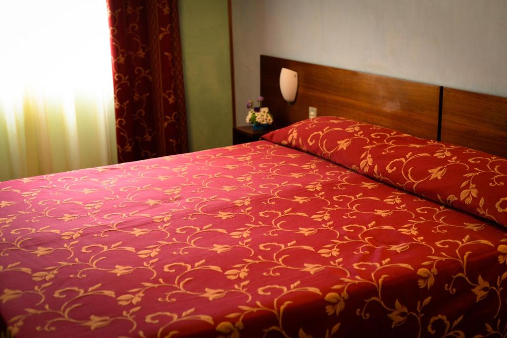 1 cama roja con edredón rojo y ventana en Hotel Salieri, en Legnago