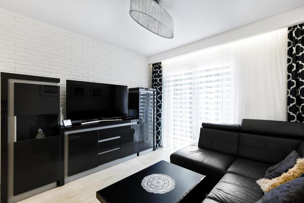 a living room with a black couch and a flat screen tv at Luxury Apartments in Kielce