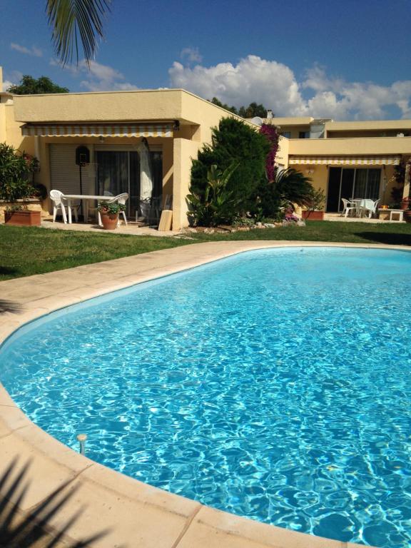 uma grande piscina azul em frente a uma casa em Villa C3 Arthur Rimbaub chambre d’hôte piscine proche mer plage 600m em Cagnes-sur-Mer