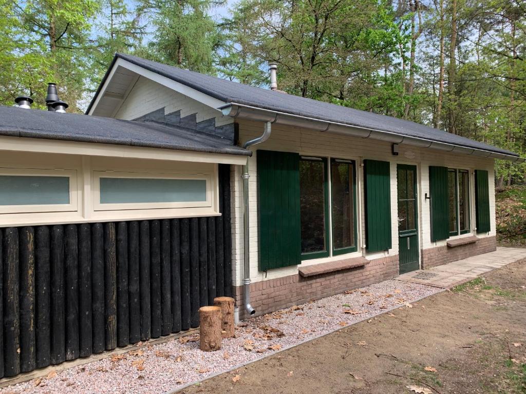 ein Haus mit einem Zaun davor in der Unterkunft Wina Boshuisje Veluwe in Otterlo