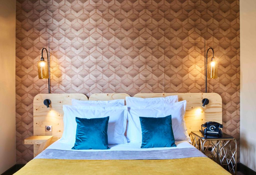 1 dormitorio con 1 cama con almohadas azules en Hotel Konti Bordeaux by HappyCulture, en Burdeos