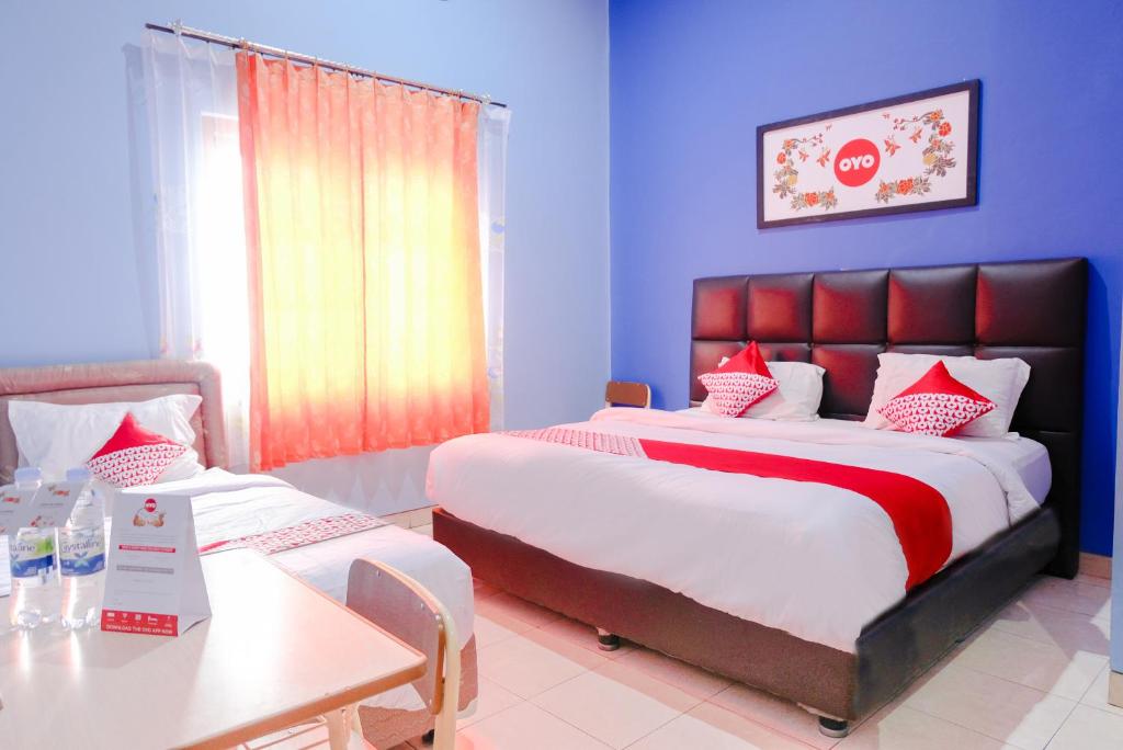 a hotel room with a large bed and a table at OYO 778 Guest House Amalia Malang in Malang