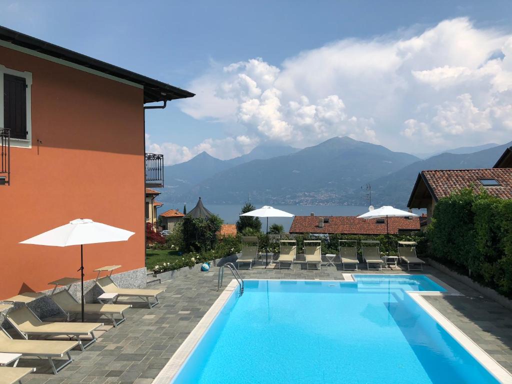 a swimming pool with chairs and umbrellas next to a building at Hotel Adler in Menaggio