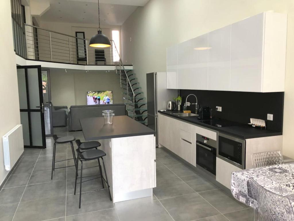 eine Küche mit einer Theke und Stühlen in einem Zimmer in der Unterkunft GRAND LOFT chic et moderne, déco industrielle in Beausoleil