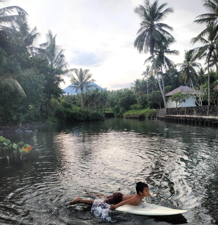 a man laying on a surfboard in the water at Jasri Dalem Surf Retreat in Jasri