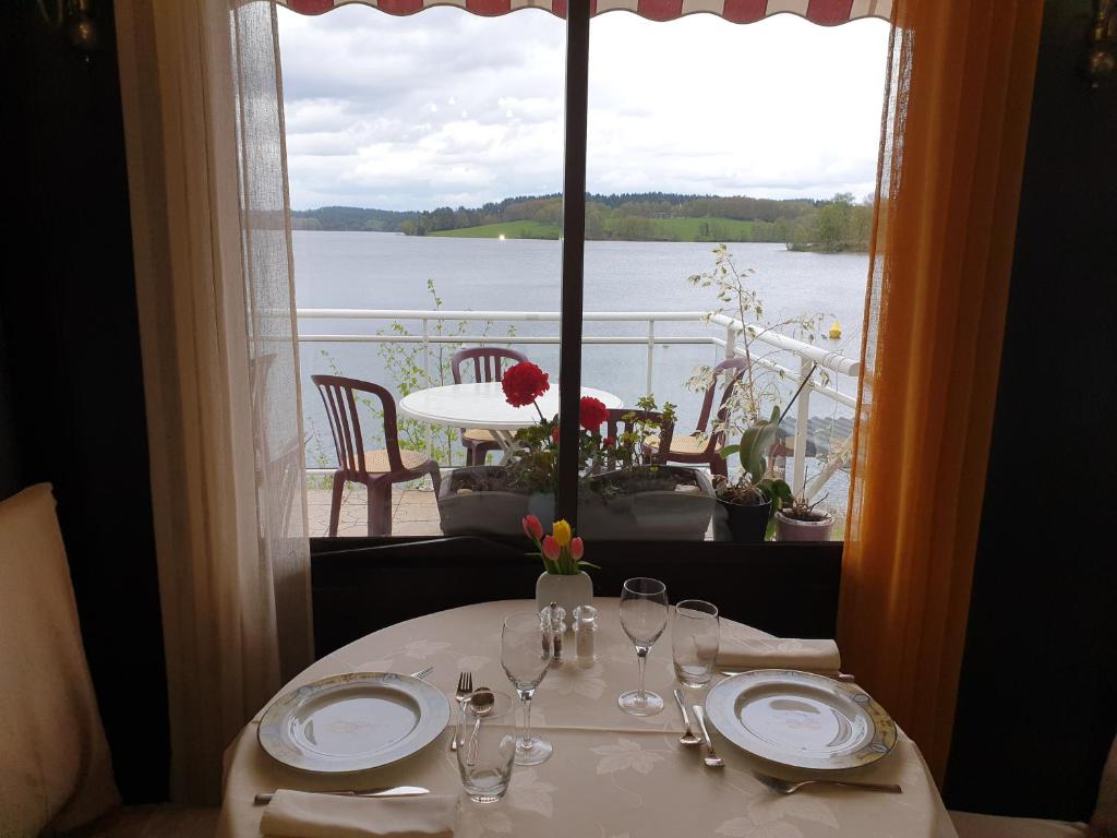 a table with a view of the water from a window at Hotel Restaurant La Caravelle in Peyrat-le-Château