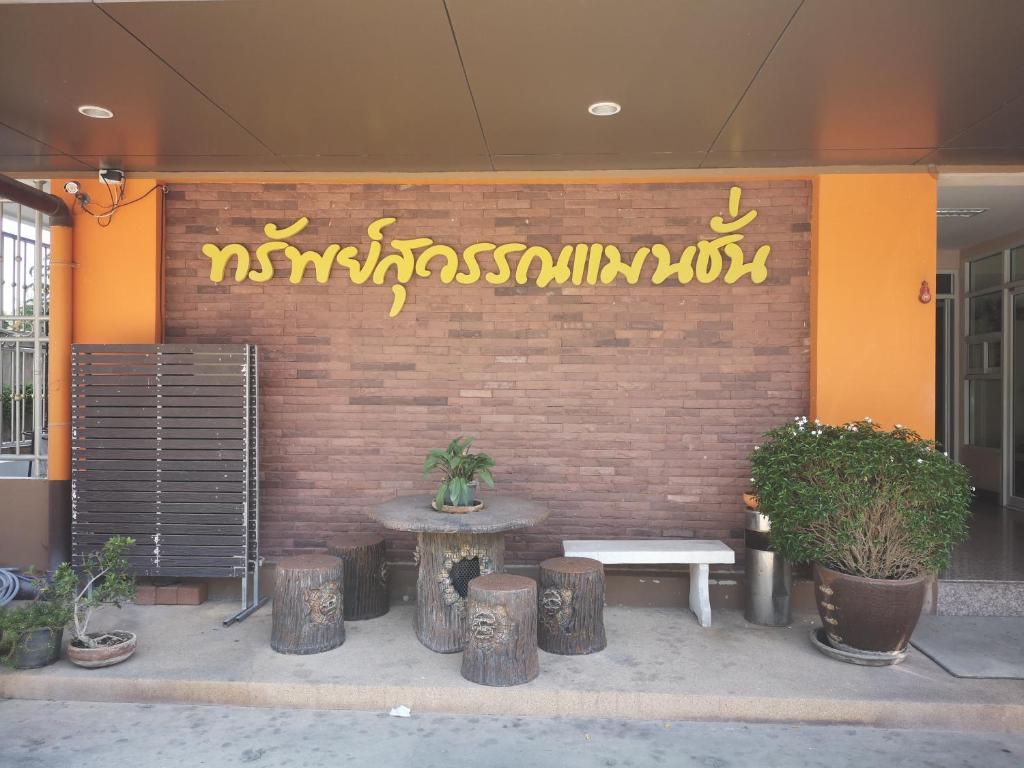 un edificio con un banco y un cartel en una pared en Sab Suwarn Mansion, en Suphanburi